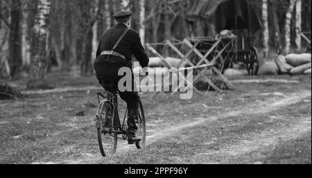 Re-enactor vestito come NKVD Forces cavalca Una bicicletta. Il Commissariato dei popoli per gli Affari interni, abbreviato in NKVD, era ministero degli interni dell'Unione Sovietica Foto Stock