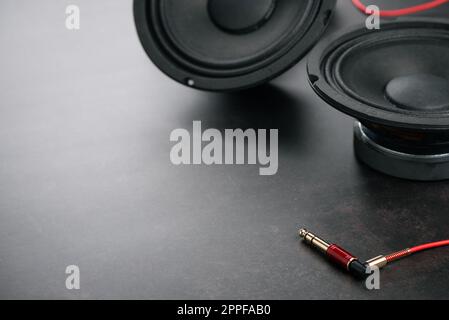Chiudere il cavo rosso AUX (ausiliario) con il jack maschio e l'altoparlante sullo sfondo. Cavo per ingresso e uscita stereo. Foto Stock
