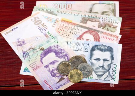 Monete e banconote di pesos colombiani su sfondo ligneo Foto Stock