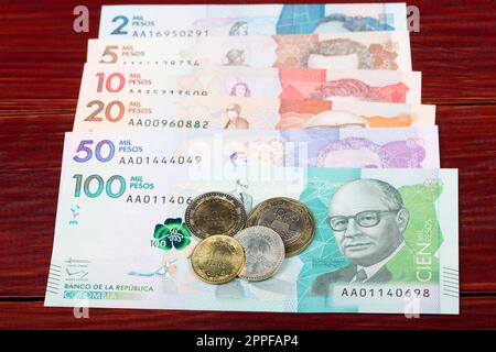 Monete e banconote di pesos colombiani su sfondo ligneo Foto Stock