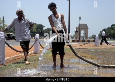 Un uomo spruzza acqua sul parco di fronte alla porta di Delhi nella città di Nuova Delhi in India. India, Delhi, febbraio, 1998 Foto Stock