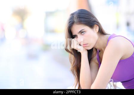 Annoiato donna in attesa di sedersi in strada Foto Stock