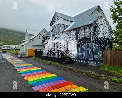 Seydisfjordur, Islanda - 23 giugno 2022: La famosa strada dell'arcobaleno a Seydisfjordur con edifici islandesi intorno mostrano pareti dipinte di opere d'arte. Foto Stock