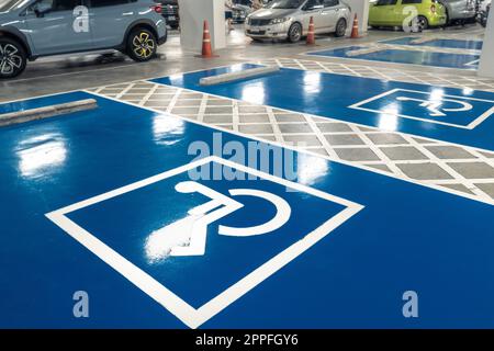 Parcheggio per auto riservato agli autisti disabili nel supermercato o nel centro commerciale. Parcheggio per disabili. Vernice segnaletica per sedie a rotelle sull'area parcheggio. Parcheggio per disabili blu e bianco. Foto Stock