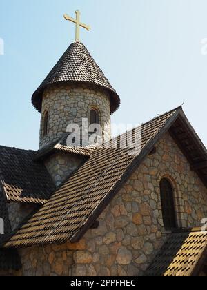 Chiesa ortodossa in pietra nel parco etno. Turismo religioso. Un edificio fatto di pietre con una croce sulla cupola. Cielo blu Foto Stock