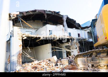 Demolizione del vecchio edificio con sloopkraan contro cielo nuvole blu. Foto Stock