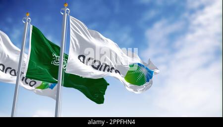 Bandiere di Aramco e dell'Arabia Saudita che sventolano in una giornata limpida Foto Stock