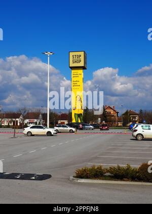 Stop and Shop, negozio di alimentari, Stop Shop Pole con marchi di marca, dipinto di giallo. Parcheggio di fronte a un grande centro commerciale. Sremska Mitrovica, Serbia, 16 marzo 2023 Shopping mania and consumerism. Foto Stock