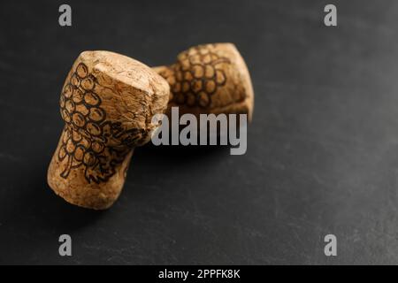 Tappi di vino frizzante con immagini d'uva su tavola nera, primo piano. Spazio per il testo Foto Stock