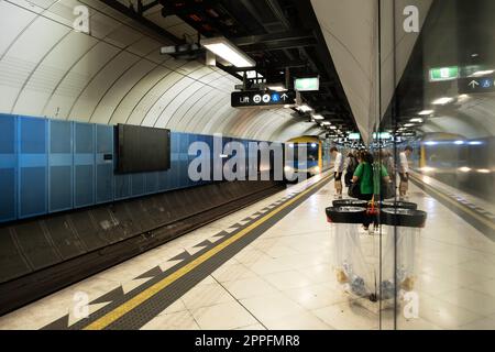 Il treno della metropolitana arriva a una piattaforma sotterranea, specchiata nel vetro. Metro Melbourne è la più grande rete ferroviaria suburbana in Australia Foto Stock