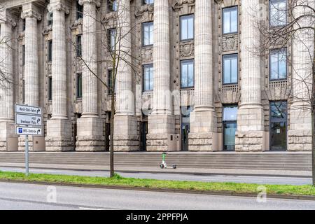 Colonia, Germania - 23 marzo 2023: Storico edificio amministrativo con un moderno scooter elettrico di fronte all'ingresso Foto Stock