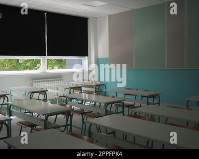 Sala conferenze con posti a sedere vuoti. Formazione per seminari aziendali. Nuova scuola moderna. Mobili bianchi. Grandi finestre con tende oscuranti o persiane. Classe scolastica vuota. Mobili e attrezzature scolastiche Foto Stock