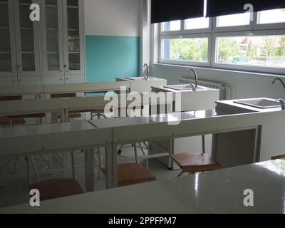 Stanza chimica in una nuova scuola moderna. Bellissimi mobili bianchi con lavandini e lavandini. Grandi finestre con tende oscuranti o persiane. Classe scolastica vuota. Mobili e attrezzature scolastiche Foto Stock