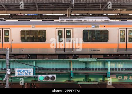 Piattaforma ferroviaria della stazione di Nakano circondata da un treno della linea JR Chuo con passeggeri all'interno. Foto Stock