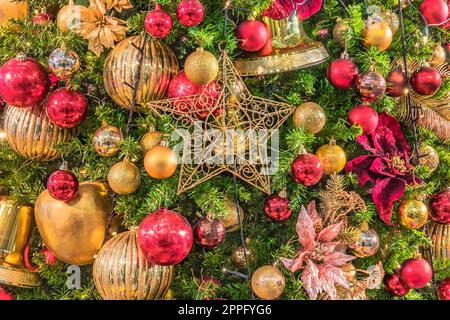 Sullo sfondo di un albero di Natale luci ornamento glitter con sfere di decorazione in primo piano. Foto Stock