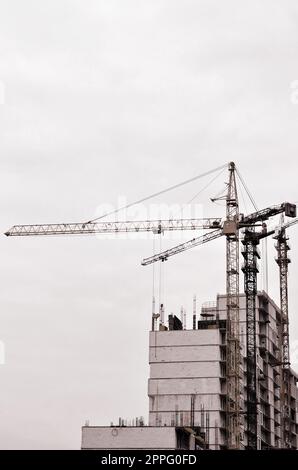 Altezza di lavoro gru interno posto per con alti edifici in costruzione contro un cielo blu chiaro. La gru e la creazione di lavoro. Tono retrò Foto Stock