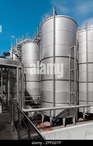 Vasche d'acciaio per la fermentazione del vino in una moderna cantina. Grandi silos di birreria per orzo o birra Foto Stock