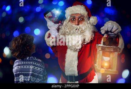 Babbo natale sta regalando un regalo di natale a un ragazzino Foto Stock