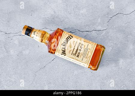 13 aprile 2021, Minsk, Bielorussia - bottiglia di miele di Jack Daniel's che si trova su fondo di cemento incrinato Foto Stock