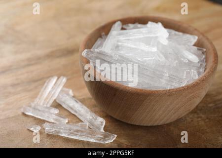 Cristalli di mentolo in ciotola su fondo di legno Foto Stock