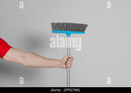 Uomo con scopa su sfondo grigio, primo piano Foto Stock