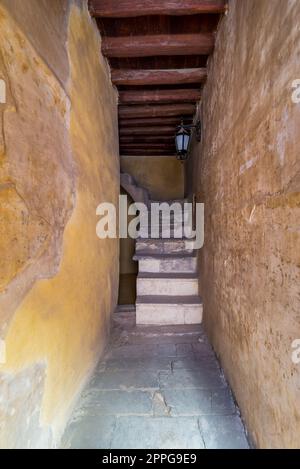 Foto di un vecchio passaggio stretto con scala in pietra e soffitto in legno Foto Stock