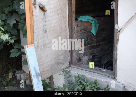 Prove con marcatore CSI giallo per la numerazione delle prove sul cortile residenziale di sera. Concetto investigativo sulla scena del crimine Foto Stock