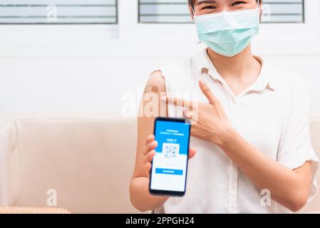 donna che punta all'adesivo sul braccio vaccinato e mostra app smartphone cellulare schermo digitale vaccinato Foto Stock