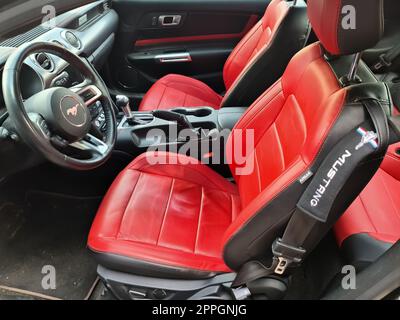 Kiel, Germania, 03. Settembre 2022: Vista laterale del volante di una vettura sportiva Ford Mustang del 2018 con sedili in pelle rossa. Foto Stock