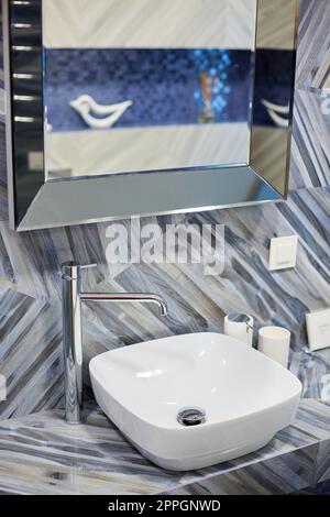 Moderno lavabo con rubinetto cromato in elegante e luminoso bagno di nuova casa. Foto Stock