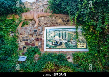 CAMBIL, SPAGNA - 14 OTTOBRE 2021: Muro di pietra a Cambil, Andalusia, Spagna, con un mosaico di piastrelle con vista sulla città sopra c'è una riproduzione di un rettile appartenente alla specie Brachychirotherium, di circa 225 milioni di anni fa, prima Foto Stock