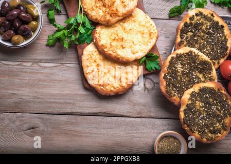 Manakeesh, pizza araba, pane piatto con spezie zaatar e formaggio. Pane piatto mediterraneo casereccio su tavolo di legno, spazio copia. Foto Stock