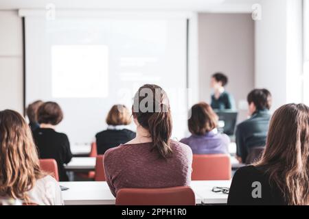 Oratrice donna che tiene una presentazione nella sala conferenze del workshop universitario . I partecipanti ascoltano la lezione e prendono appunti. Conferenza scientifica Foto Stock