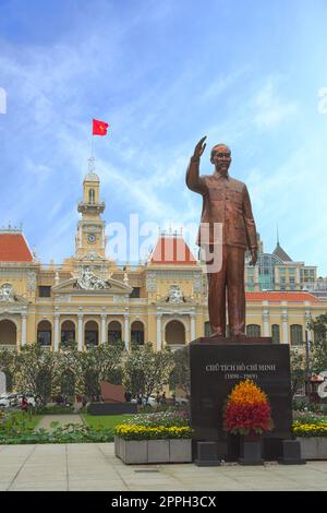 Statua di Ho Chi Minh con bandiera vietnamita in background, davanti a Saigon City Hall, Vietnam. Foto Stock