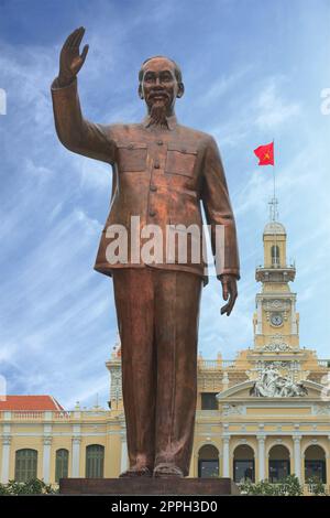 Statua di Ho Chi Minh con bandiera vietnamita in background, davanti a Saigon City Hall, Vietnam. Foto Stock