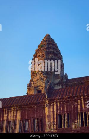 Angkor Wat, in Cambogia. Vista angolare bassa di una delle torri centrali al tramonto contro il cielo blu. Foto Stock