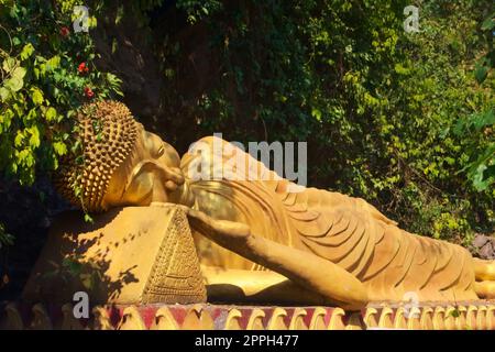 Statua dorata di Buddha reclinato sulla strada per la cima del Monte Phou si, una montagna sacra a Luang Prabang, Laos. Foto Stock