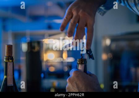 Mani di un sommelier che apre una bottiglia di vino con un cavatappi. Foto Stock