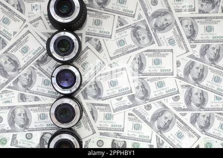 Alcuni obiettivi fotografici si trovano sullo sfondo di un sacco di bollette in dollari. Spazio per il testo Foto Stock