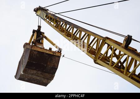 Vecchia benna mordente meccanica gialla su sfondo cielo blu Foto Stock