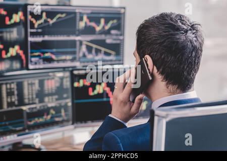 Oltre la spalla di stock broker trading online, parlando al telefono cellulare. Foto Stock