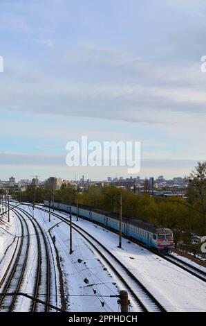 Paesaggio invernale con un treno ferroviario sullo sfondo di un cielo nuvoloso Foto Stock