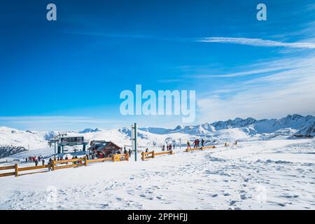 Sciatori e snowboarder si preparano a salire sulle piste vicino agli impianti di risalita di Andorra Foto Stock