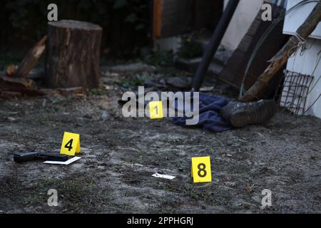 Prove con marcatore CSI giallo per la numerazione delle prove sul cortile residenziale di sera. Concetto investigativo sulla scena del crimine Foto Stock