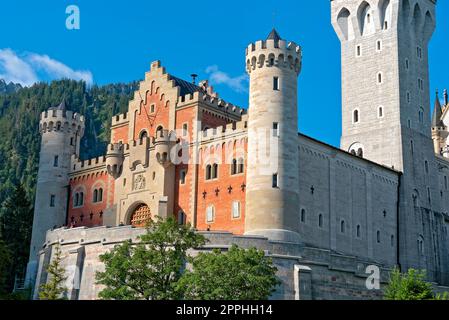 Vista frontale della facciata del Castello di Neuschwanstein con area d'ingresso e castello esterno nelle belle giornate Foto Stock