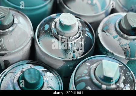 Un sacco di bombolette spray usate di vernice primo piano. Lattine sporche e sbavate per il disegno di graffiti. Il concetto di un disegno di vernice sinuoso e disattento. Immagine artistica creativa Foto Stock