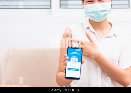 donna che punta all'adesivo sul braccio vaccinato e mostra app smartphone cellulare schermo digitale vaccinato Foto Stock