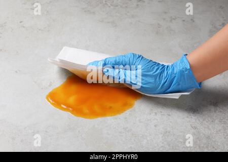 Donna strofinando la salsa con carta assorbente sulla superficie grigia, primo piano Foto Stock