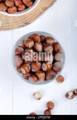 Nocciole sgusciate in una ciotola su fondo di legno bianco. Vista dall'alto. Foto Stock