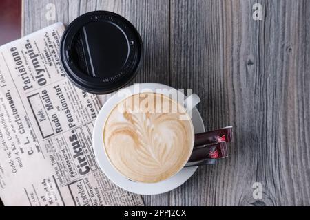 Tazza di caffè in ceramica e cartone su un tavolo di legno vicino al giornale. Vista dall'alto. Foto Stock